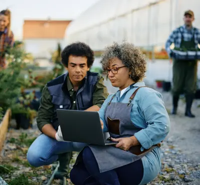 2 indivduals collaborate on laptop in plant nursery